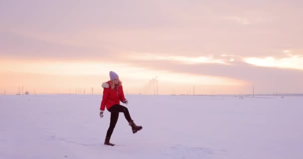 Femme marche dans un champ de neige et jette de la neige avec son pied — Video