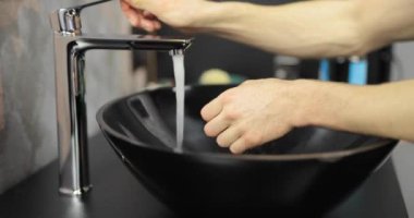 Erkek elleri musluğu aç ve ellerini yıka.