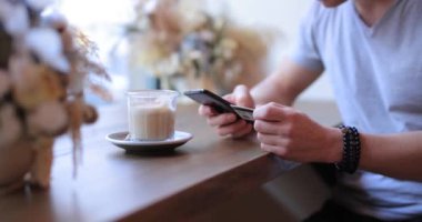 Tanınmayan kişi kahve içer ve akıllı telefon kullanır.