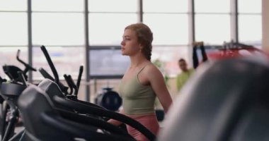 Spor salonunda koşu bandında yürüyen bir kadın.