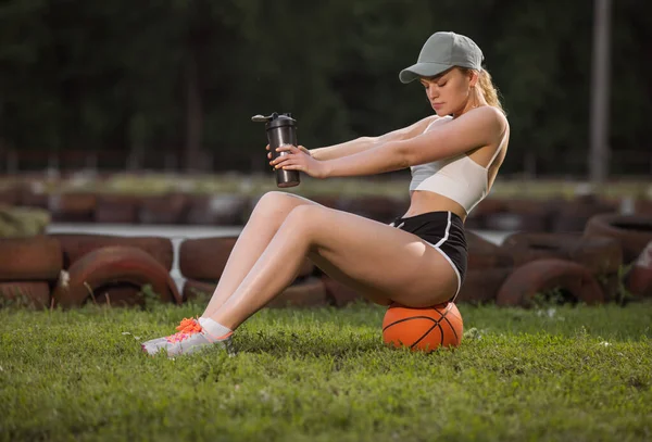 Jaki sport lubisz najbardziej? woman with shaker sitting on a basketball — Zdjęcie stockowe