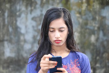 Teenage asian girl using mobile phone. Young lady reading text messages on smartphone screen