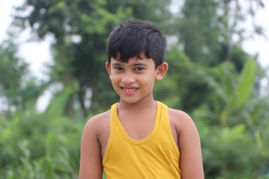 Mutlu gülümseyen küçük çocuk dışarıda fotoğraflara poz veriyor.