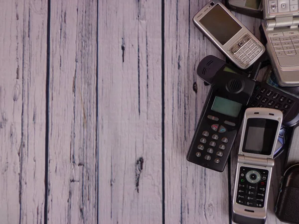 Old mobile phones arranged on a wooden base and retro environment, with space to place text.