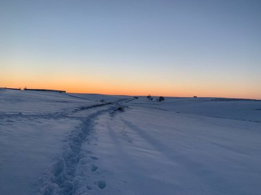 Gün batımında karda ayak izleri.