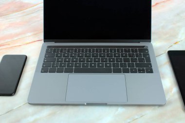 Yanında tablet, cep telefonu ve mermer zemin üzerinde ofis malzemeleri bulunan bir bilgisayarın üst görüntüsü