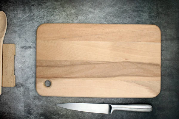 Food cutting board accompanied by a steel knife and wooden cutlery