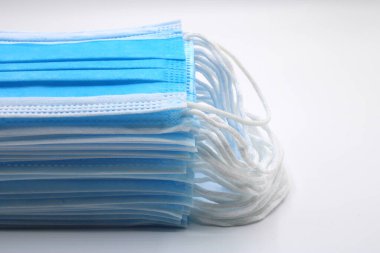 Beyaz arka planda cerrahi maskeler birikti.