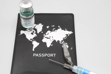 Pasaportun yanında şırınga ve aşı şişesi var.