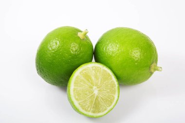Beyaz arka planda tam ve yarım dilim yeşil limon..