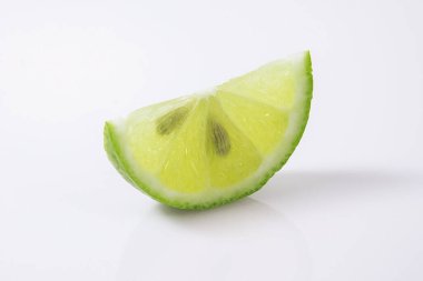 Beyaz arka planda çeyrek yeşil limon.