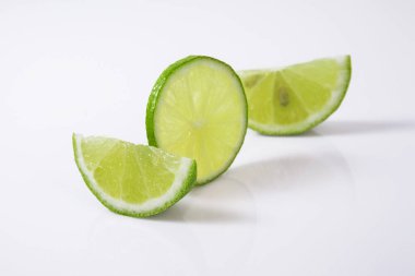 Beyaz arka planda çeyrek dilim yeşil limon..