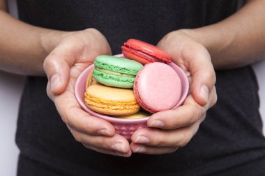 Tatlı ve renkli makaronlu kadın elinde siyah arka planda.