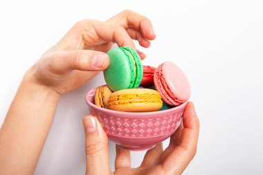 Beyaz arka planda tatlı ve renkli makaronlu bir kadın var..