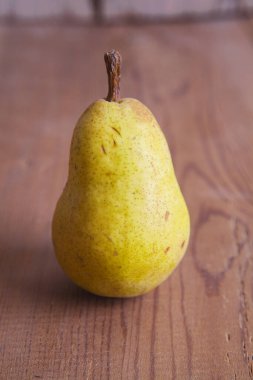 Tahta arka planda izole edilmiş güzel, taze, sarı bir armut..