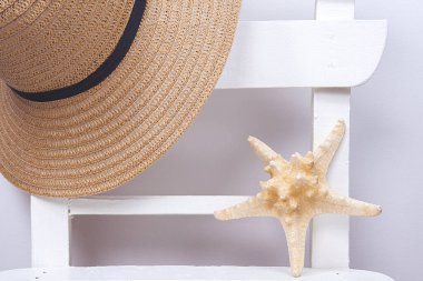 Güneşli bir günde denizyıldızı ve hasır şapka. Rahatlama konsepti.