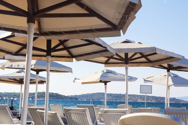 Deniz kenarında güneşli bir günde plaj şemsiyeleri ve sandalyeler.. 