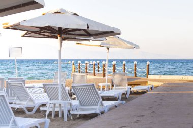 Deniz kenarında güneşli bir günde plaj şemsiyeleri ve sandalyeler.. 