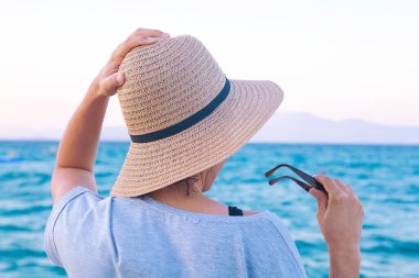 Yaz konseptiyle sahilde yürüyen bir kadın..