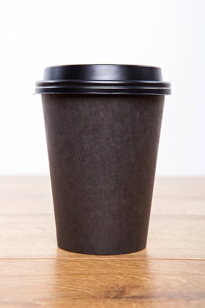 Disposable coffee cup over wooden background.