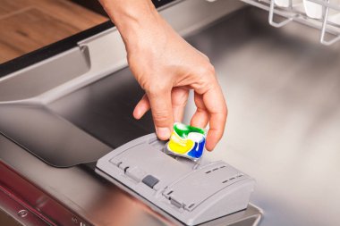 Bulaşık makinesinde bulaşık yıkamak için kadın eliyle bulaşık deterjanı..