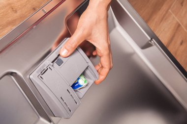 Bulaşık makinesinde bulaşık yıkamak için kadın eliyle bulaşık deterjanı..