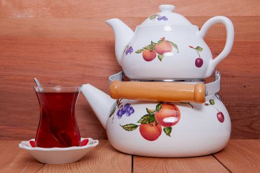 Ahşap zeminde çaydanlık ve bir fincan çay..