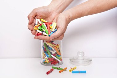 Küçük rulo dilek kağıtları ve beyaz arka planda bir kavanoz. Dilek kavanozu Dilek kavramı. Hayal, arzu, arzu, niyet. Kadın kavanozdan niyetini belli ediyor..