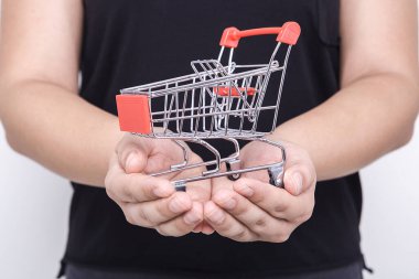 İnternetten alışveriş yapan kadının elindeki küçük oyuncak alışveriş arabası. İnternet alışveriş kavramı.