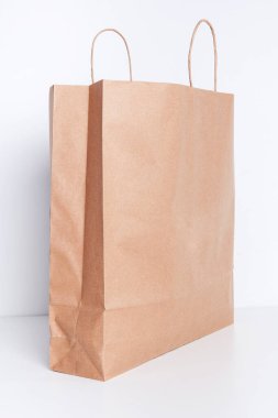 Beyaz arka planda kahverengi kağıt alışveriş torbası.