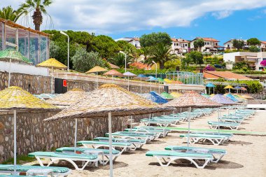 Deniz kenarında güneşli bir günde plaj şemsiyeleri ve sandalyeler.. 