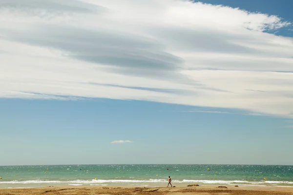 Single person walking on a beach under a big cloud — Stock Photo, Image