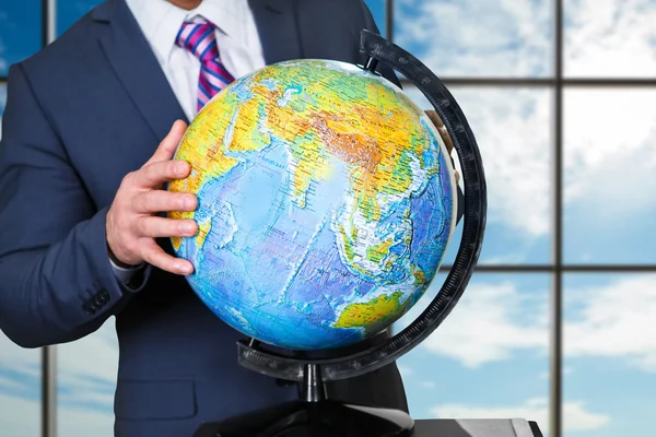 Businessman holds globe near window. — Stock Photo, Image