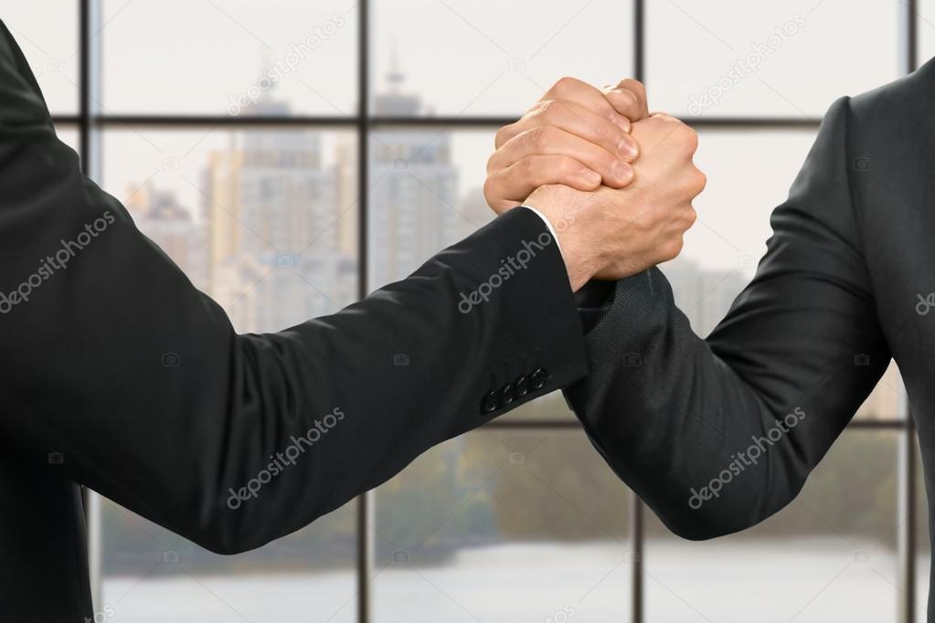 Businessmens strong and friendly handshake.