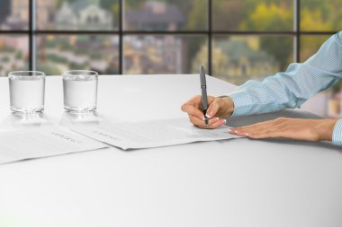 Woman signs contract at office.