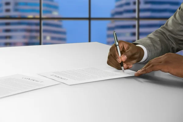 Afroamerican podpisuje dokument w biurze. — Zdjęcie stockowe