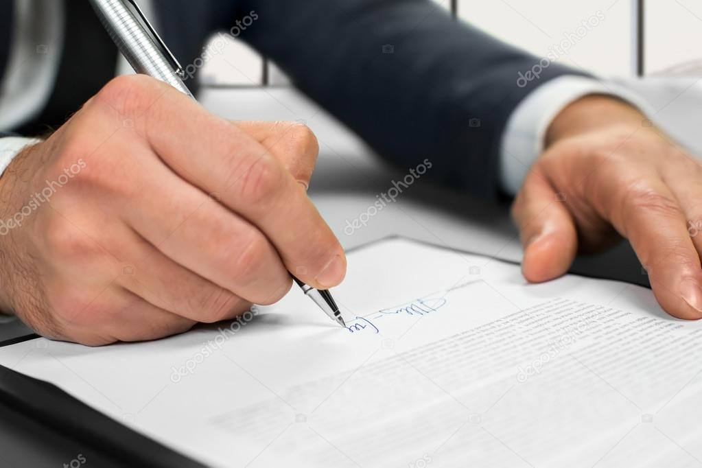 Businessman signing contract at office.