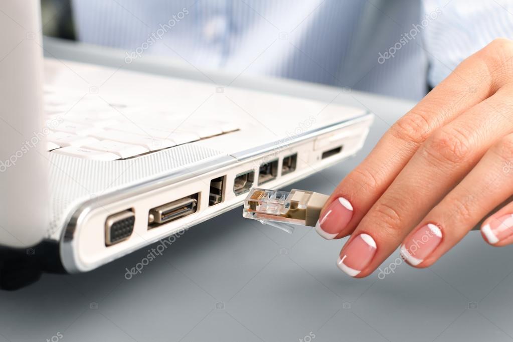 Womans hand plugging network cable.
