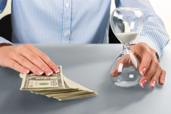 Kadın nakit ve kum saati dokunur.