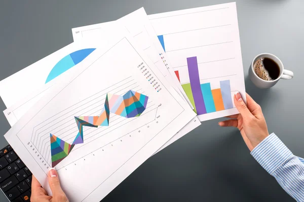 Női kezében tartsa grafikus diagramok. — Stock Fotó