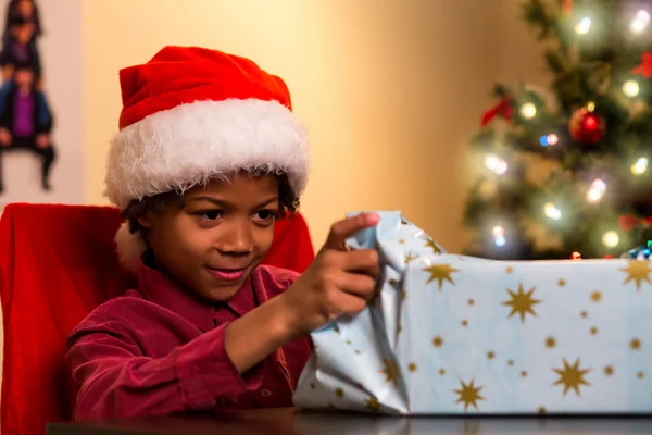 Niño negro abriendo regalo de Navidad . — Foto de Stock