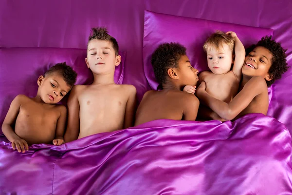 Cinco niños en la cama púrpura . — Foto de Stock