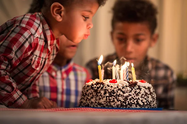 Black toddler blowing candles out.