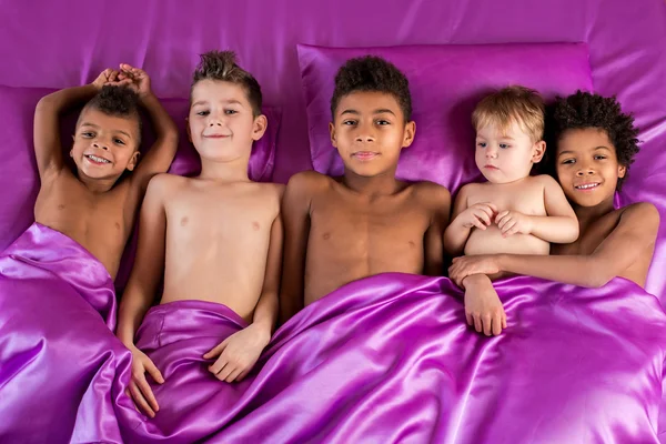 Radostné děti na fialové postel. — Stock fotografie