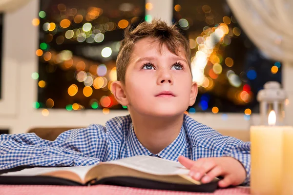 Enfant avec livre près d'une bougie . — Photo