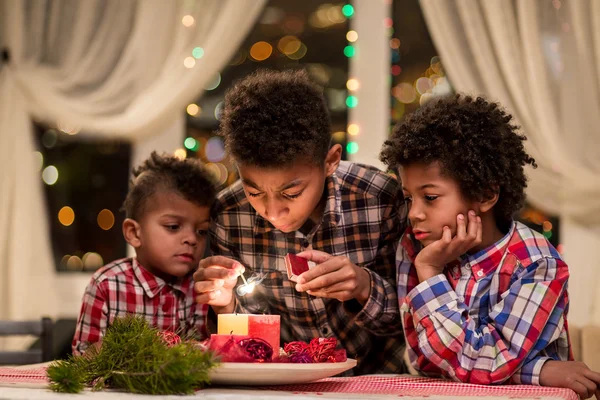 Crianças afro acendendo velas de Natal . — Fotografia de Stock
