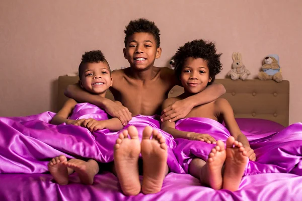 Chicos sonrientes se sientan en la cama . — Foto de Stock