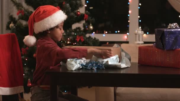 Niño negro abriendo regalo de Navidad . — Vídeo de stock