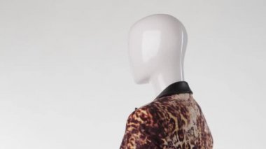 Mannequin in leopard blazer turning.