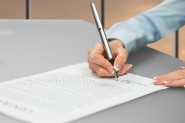 Young ladys hand signing document.